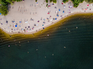 Aerial view from a drone of people who are resting on the sandy shore of the beach by the river