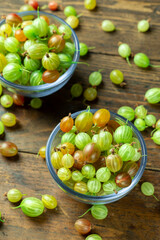 Sweet fresh gooseberry berry in a bowl on wood background.