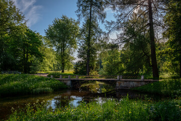 Fototapeta na wymiar The bridge over the Upper Ponds to the kitchen ruins in Catherine Park in Tsarskoye Selo on a sunny summer evening. Pushkin, St. Petersburg. Russia.