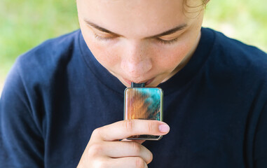 A pretty young girl is holding a popular gadget, a vaping device. A happy brunette vaper with an...