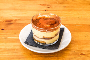 Tiramisu dessert with lots of cocoa powder inside a crystal glass served in an Italian restaurant