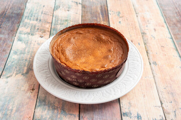 Freshly baked whole cheesecake on white plate.