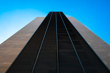Symbolic tall building with a perspective of power, minimalist construction towards the blue sky, symmetrical design for contemporary backgrounds.