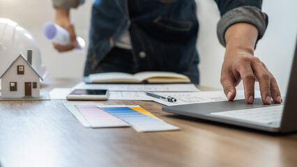 Interior designer choosing color in color swatch samples chart for house coloring selection in office with blueprint. Construction concept.