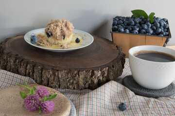Blueberry muffin, fresh seasonal blueberries in an antique basket with a black cup of coffee.
