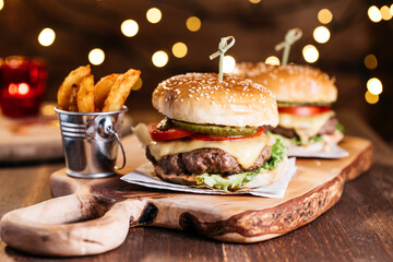 Classical cheeseburger with baked potatoes served on wooden board in holiday spirit