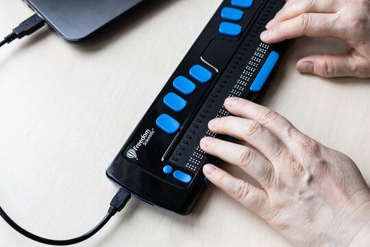 Moscow, Russia - June 5, 2021: fingers read with Focus 40 Blue Braille Display. Freedom Scientific is the largest manufacturer of assistive technology products for blind and low vision people