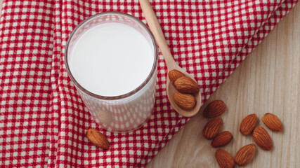 almond milk in glass and spoon with nuts are around on red cloth on wood background. selective focus.top view, top-down, flat lay.