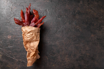 Jerky meat strips with spices and herbs on a paper on a dark background. Tipical Italian food coppiette is a spiced pork meat strips. Snacks for beer, top view, copy space