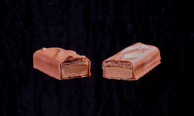 Two chocolate bars floating in the air, with a black background.