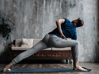 A young man performing yoga asanas and sports exercises to improve the strength and flexibility of the body