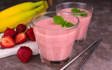 Two glasses of strawberry banana smoothies on a gray background.