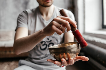 A young male yogi playing a musical instrument a Tibetan singing bowl