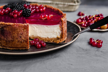 cheesecake topped with raspberry jelly, garnished with blackberries and red currants 