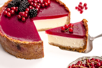 cheesecake topped with raspberry jelly, garnished with blackberries and red currants 