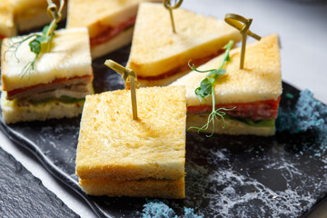 Sandwiches with smoked sausage on wooden skewers.
