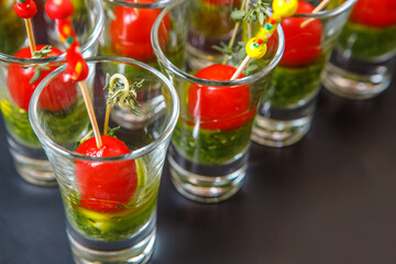 Snacks of tomatoes and cucumbers on skewers in glass glasses.