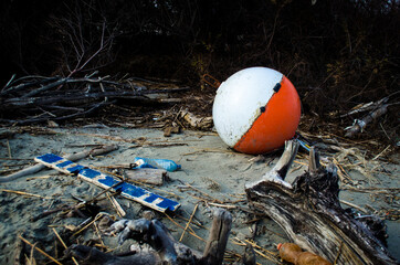 Una vecchia boa di plastica depositata sulla spiaggia dalla marea insieme a due bottiglie di...