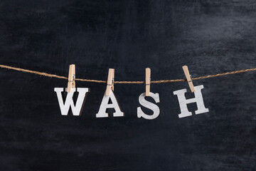 Word WASH with clothespins on black background. Concept of laundry service.