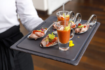 The waiter holds a tray with light snacks in his hands
