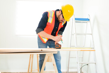 Male engineer using a measuring tape to cut wood