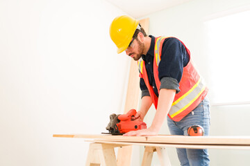 Carpenter with protective gear cutting wood