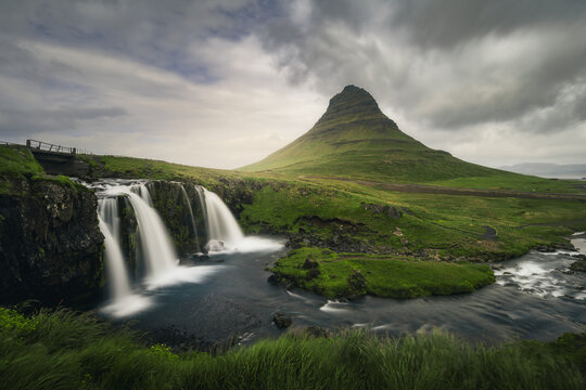 Scenic view of Kirkjufell mountain and Kirkjufellfoss waterfall against dramatic cloudy sky, Iceland, Sn&aelig;fellsnes peninsula