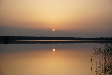 Fototapeta na wymiar Summer evening in July. Sunset over the lake after a hot day. Quiet charm and reflection. Horizon