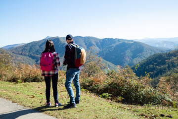 Obraz premium Father and his teenage daughter hiking looking the landscape of mountains
