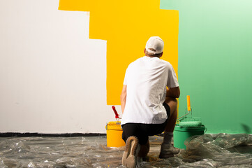 Male decorator looks at a green-yellow painted wall