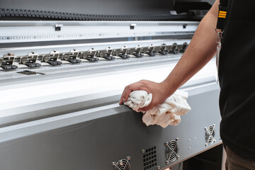 Person cleaning a printing plotter. Hands clean large format machine.