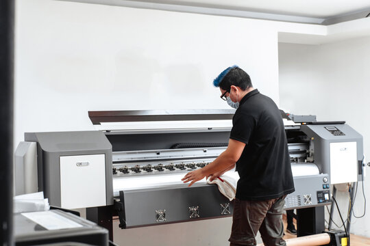 Latin American man with mask cleaning large format plotter. concept business and corona virus.