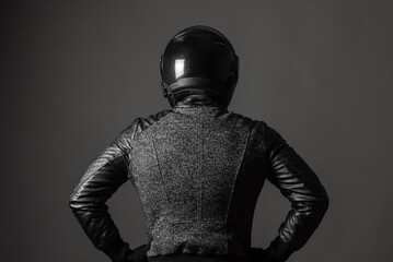 Motorbiker with a hands on his belt looks forward. Back view.