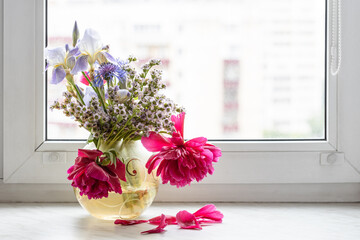 withered flowers in glass vase on window sill