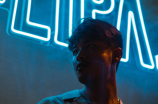 Portrait Of Handsome Asian Man In Front Of Blue Neon Lights