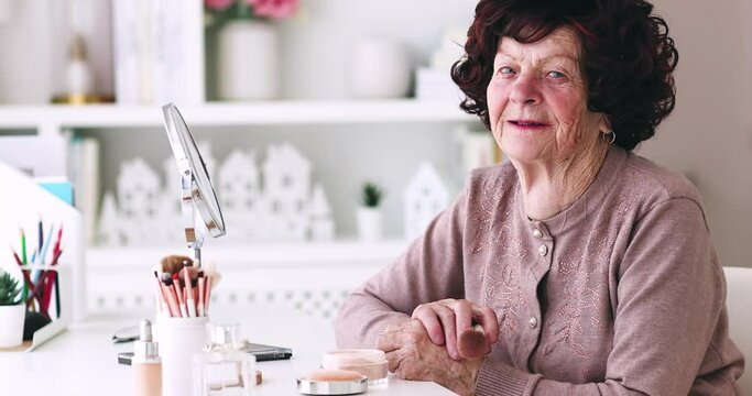 portrait of cheerful senior woman applying her makeup on, at home, 84 years old lady