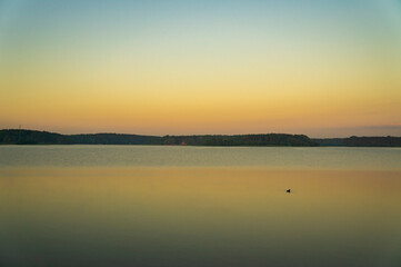 Fototapeta na wymiar Calm beautiful sunrise over the lake with sky reflection in water