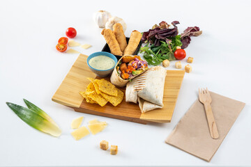 Super and colorful burrito with wheat tortilla, green sauce, avocado and fried chicken, purple color and carrot, corn nachos, Venezuelan tequeños on white background.