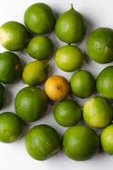 Textura de limones verdes con un limón amarillo en fondo blanco