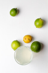 Limones y vaso con limonada en fondo blanco 