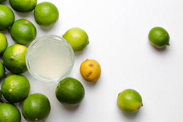 Limones y vaso con limonada en fondo blanco 