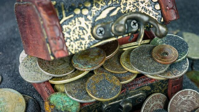 The antiquarian wooden chest with coins closeup rotation on a black sand.