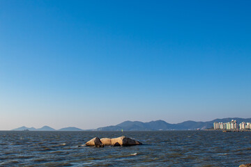 island in the sea and Brazilian flag flying on top of a rock in Florianópolis