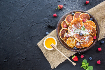 A healthy breakfast of cheese pancakes, berries, and honey. Creative atmospheric decoration