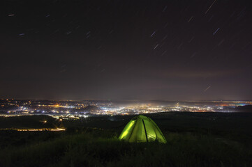 Night landscape, tent against the background of the starry sky and city lights on a hill in Ukraine