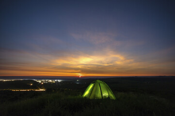 Fototapeta na wymiar Morning landscape, tent against the background of sunrise and city lights on a hill in Ukraine