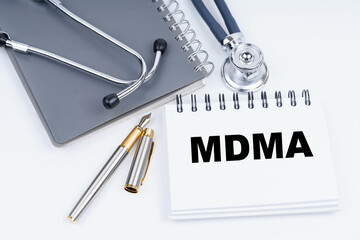 On the table are a stethoscope, a pen and a notebook with the inscription - MDMA