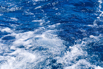 Fototapeta na wymiar Abstract blue sea water with white wave for background. Adreatic sea, blue mediterranean sea. sea splash sailing boat trail on the water