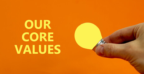 Our core values symbol. Businessman holds yellow shining light bulb. Words 'Our core values'....
