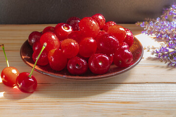  Selected cherry berries. Ceramic saucer, wooden background. Topic: delicious and healthy food